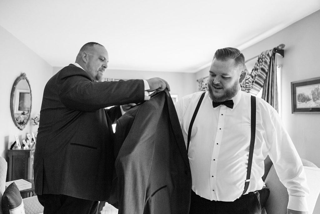Best man puts jacket on groom