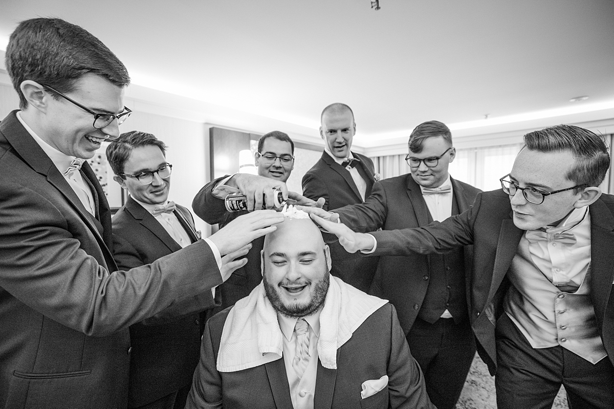 Groomsmen shaving groom's head